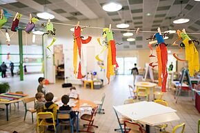 une salle d'accueil périscolaire décorée par les enfants, dont on devine quelque uns assis autour d'une tabl